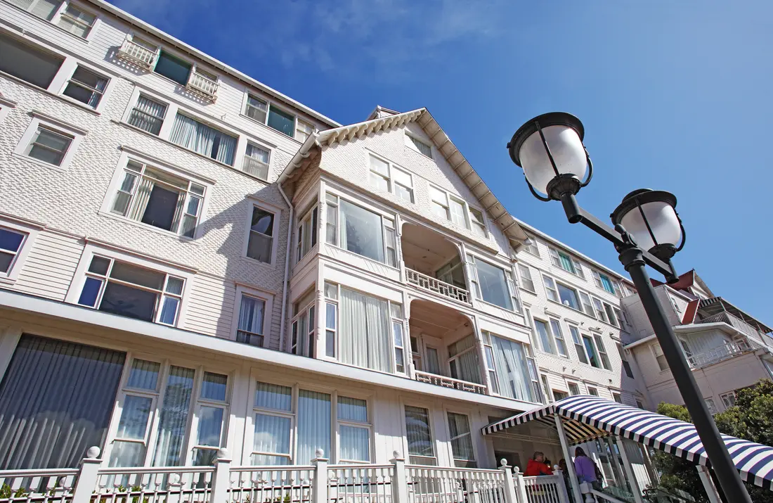 A modern photograph of the Hotel del Coronado's red-roofed Victorian side entrance and turret.