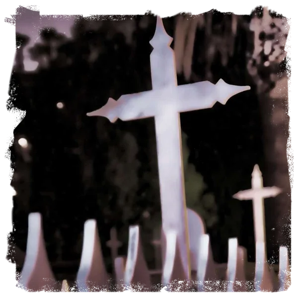 A weathered memorial cross standing among the gravestones in the historic El Campo Santo cemetery in San Diego.